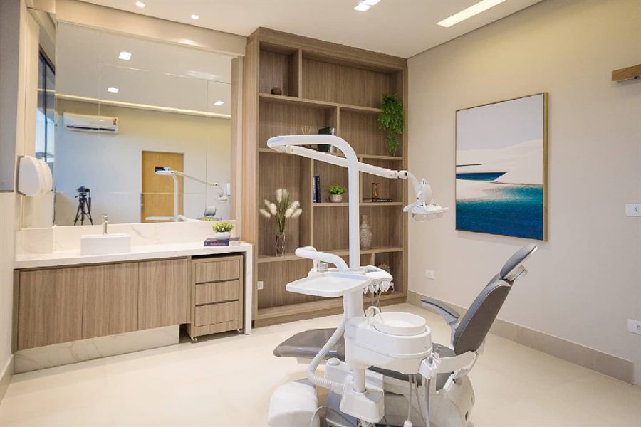 Consultório da Odontologia França com cadeira odontológica, bancada de mármore e estante de madeira