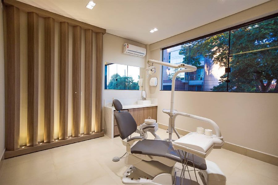 Consultório da Odontologia França com painel de madeira iluminado e janela ampla com vista para as árvores